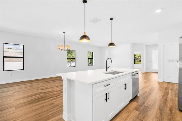 kitchen with a wealth of natural light, stainless steel dishwasher, light wood-type flooring, and a sink