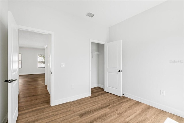 unfurnished bedroom with visible vents, baseboards, and wood finished floors