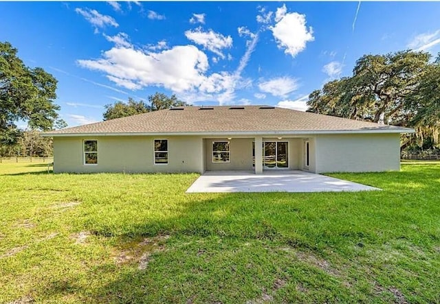 rear view of house with stucco siding, a patio, and a yard