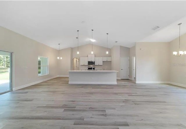 kitchen with a chandelier, open floor plan, white cabinetry, and stainless steel appliances