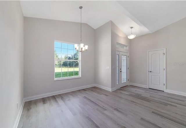 entryway featuring a notable chandelier, wood finished floors, baseboards, and high vaulted ceiling