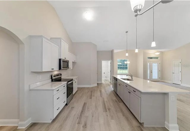 kitchen with light wood finished floors, light countertops, appliances with stainless steel finishes, white cabinets, and a sink