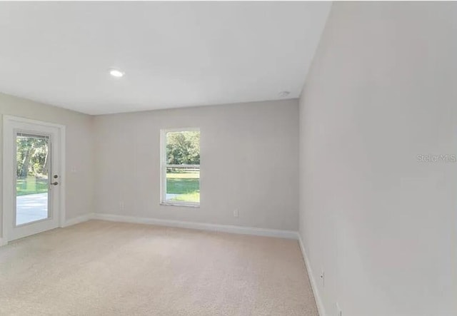 unfurnished room with baseboards, light colored carpet, and a healthy amount of sunlight