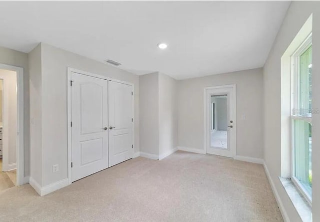 unfurnished bedroom featuring baseboards, visible vents, a closet, and light carpet