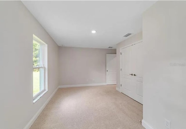 unfurnished room with light carpet, visible vents, and baseboards