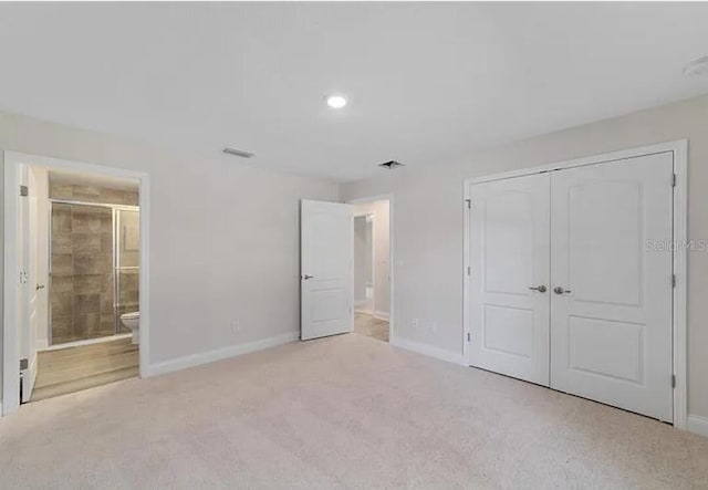 unfurnished bedroom with visible vents, baseboards, carpet flooring, ensuite bathroom, and a closet