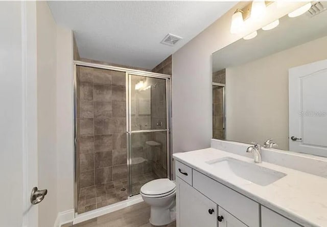 bathroom with visible vents, vanity, toilet, and a shower stall