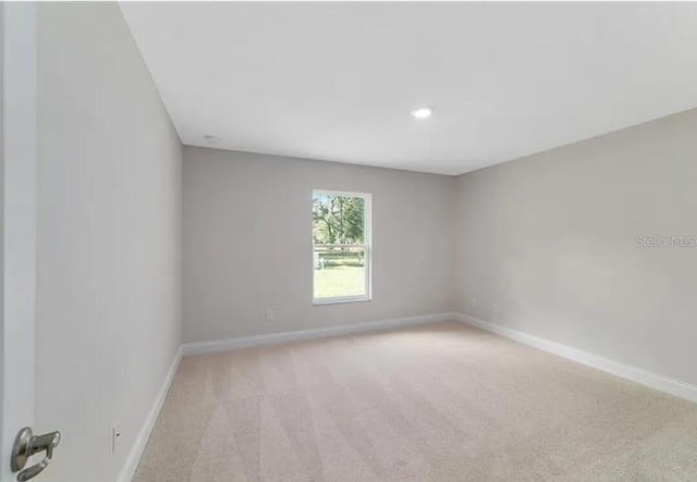 unfurnished room featuring baseboards and light carpet