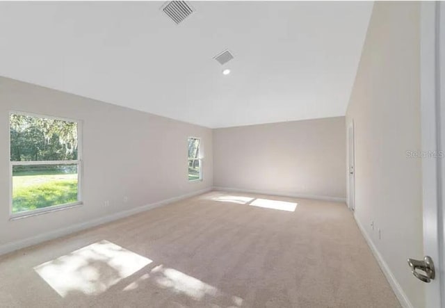 empty room with light colored carpet, visible vents, and baseboards