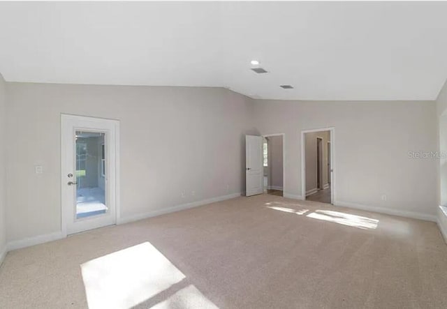 carpeted empty room featuring baseboards and lofted ceiling