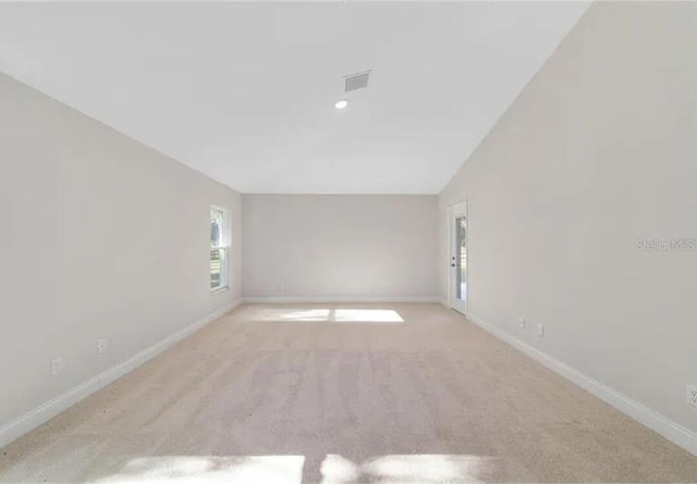 empty room featuring visible vents, lofted ceiling, baseboards, and carpet floors