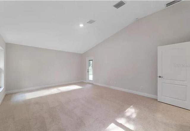 empty room featuring visible vents, baseboards, high vaulted ceiling, and carpet flooring