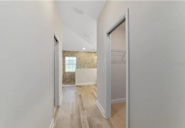 hallway with visible vents, light wood-style floors, and baseboards