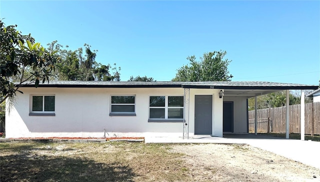 view of front of home with stucco siding, an attached carport, driveway, and fence