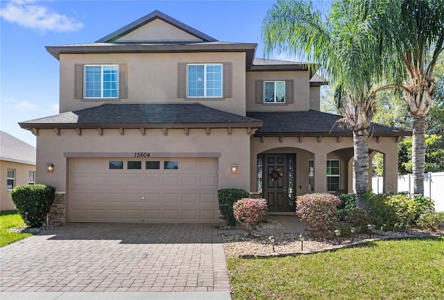 view of front of house with stucco siding, decorative driveway, and an attached garage