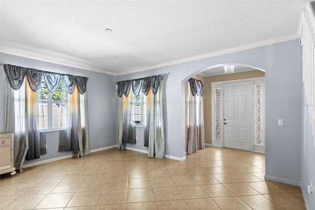 spare room featuring light tile patterned floors, baseboards, arched walkways, and crown molding