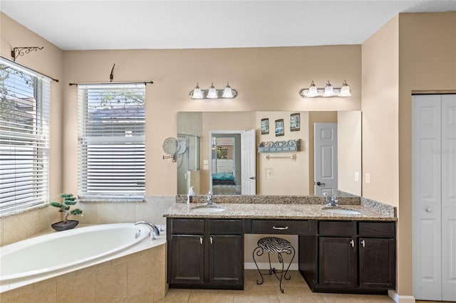 bathroom featuring a sink, a bath, double vanity, and tile patterned flooring