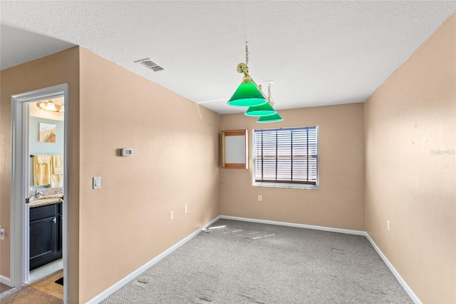 carpeted empty room with baseboards, visible vents, and a textured ceiling