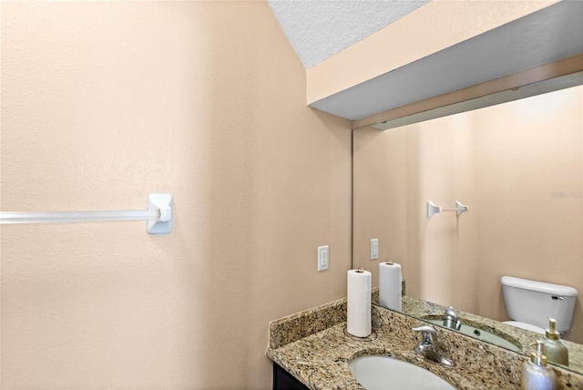 half bath featuring vanity, toilet, and a textured ceiling