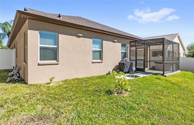 back of house featuring stucco siding, a lawn, glass enclosure, and fence