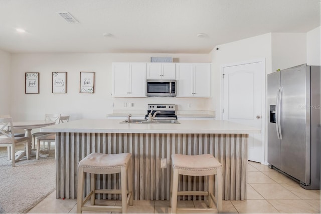 kitchen with a sink, a kitchen breakfast bar, white cabinetry, appliances with stainless steel finishes, and light countertops