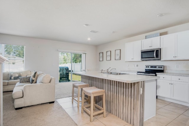 kitchen featuring a sink, open floor plan, appliances with stainless steel finishes, plenty of natural light, and a kitchen island with sink