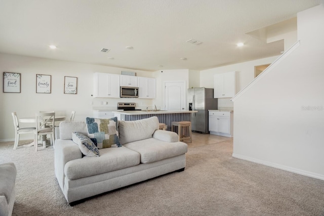 living room featuring recessed lighting, visible vents, light colored carpet, and baseboards