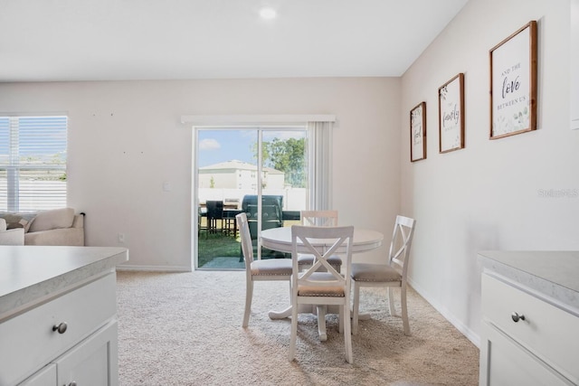 dining room featuring light colored carpet, baseboards, and a healthy amount of sunlight