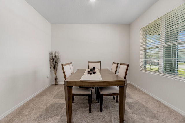 dining space featuring light carpet and baseboards