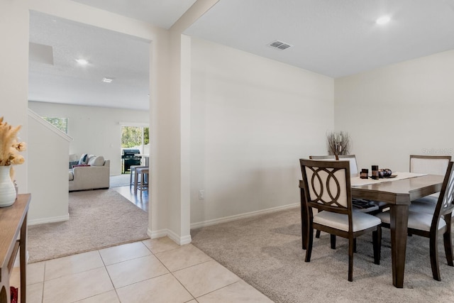 dining space featuring light tile patterned flooring, baseboards, visible vents, and light carpet