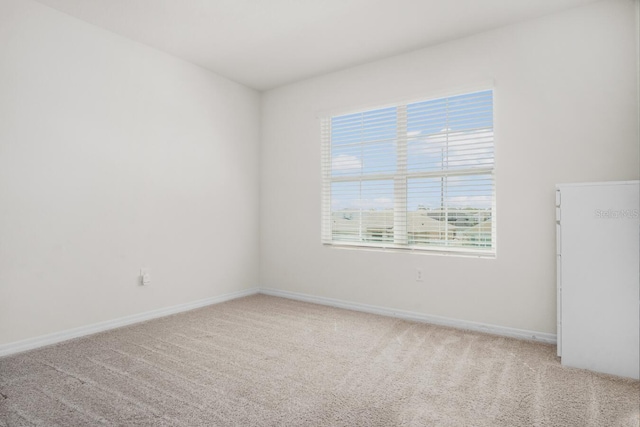 empty room featuring baseboards and light carpet