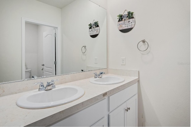 full bathroom with double vanity, toilet, and a sink