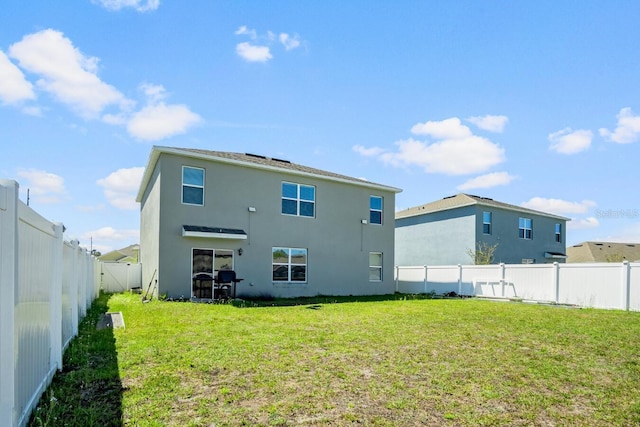 rear view of property with stucco siding, a lawn, and a fenced backyard