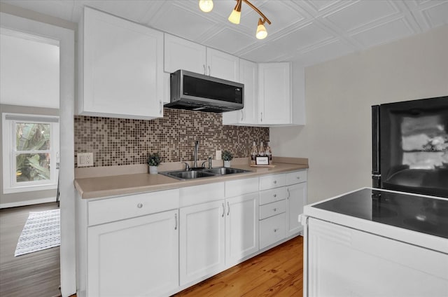 kitchen with a sink, stainless steel microwave, an ornate ceiling, decorative backsplash, and range