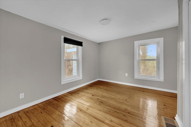 empty room with visible vents, baseboards, and hardwood / wood-style flooring