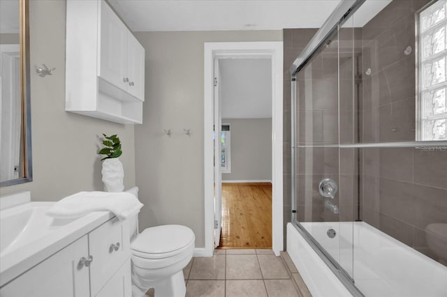 full bathroom featuring vanity, baseboards, shower / bath combination with glass door, tile patterned flooring, and toilet