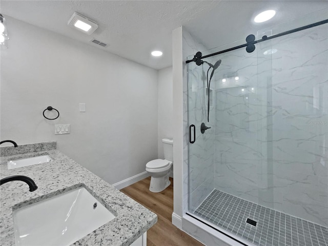 bathroom featuring visible vents, a stall shower, wood finished floors, and a sink