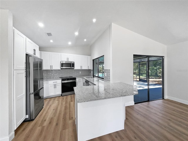 kitchen with tasteful backsplash, visible vents, lofted ceiling, appliances with stainless steel finishes, and a peninsula