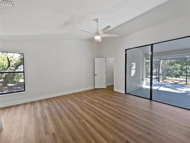 spare room with a ceiling fan, wood finished floors, a healthy amount of sunlight, and visible vents