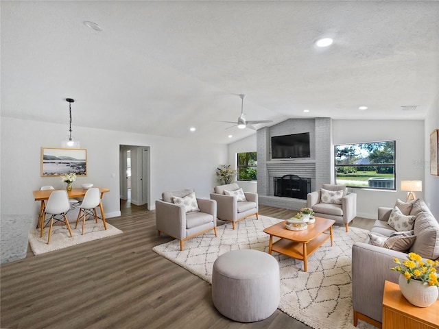 living area featuring lofted ceiling, a healthy amount of sunlight, wood finished floors, and a ceiling fan