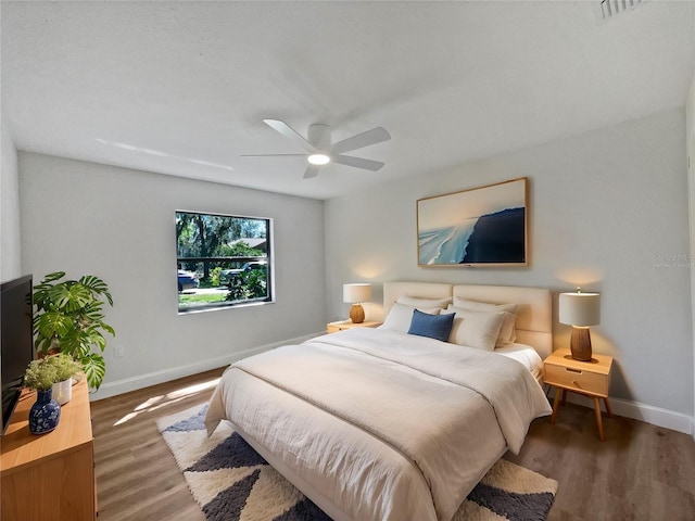 bedroom with a ceiling fan, baseboards, and wood finished floors