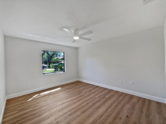 spare room featuring wood finished floors, baseboards, and ceiling fan