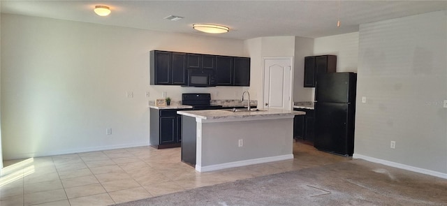 kitchen with dark cabinetry, a center island with sink, visible vents, a sink, and black appliances