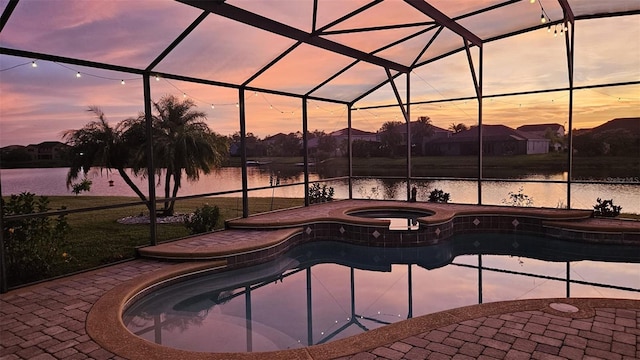 pool at dusk featuring a patio, a lanai, and a water view