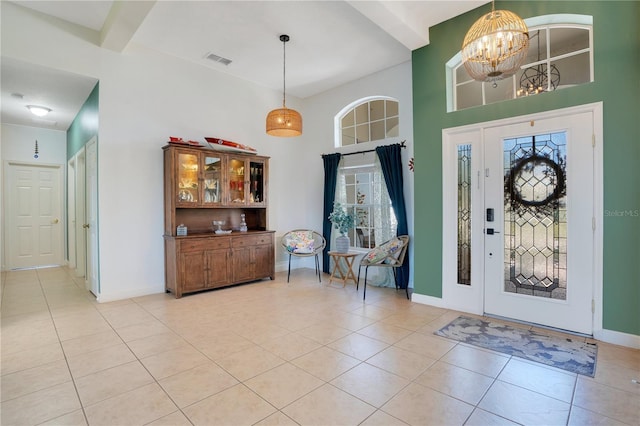 foyer featuring light tile patterned floors, beamed ceiling, baseboards, and a chandelier