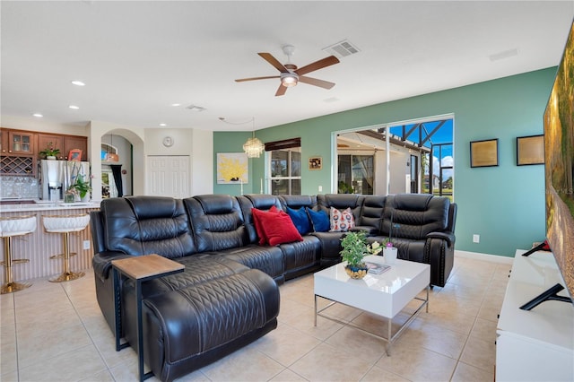 living area featuring light tile patterned floors, visible vents, arched walkways, and a ceiling fan