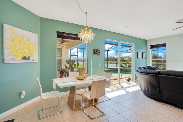 dining room with light tile patterned flooring, ceiling fan with notable chandelier, and baseboards