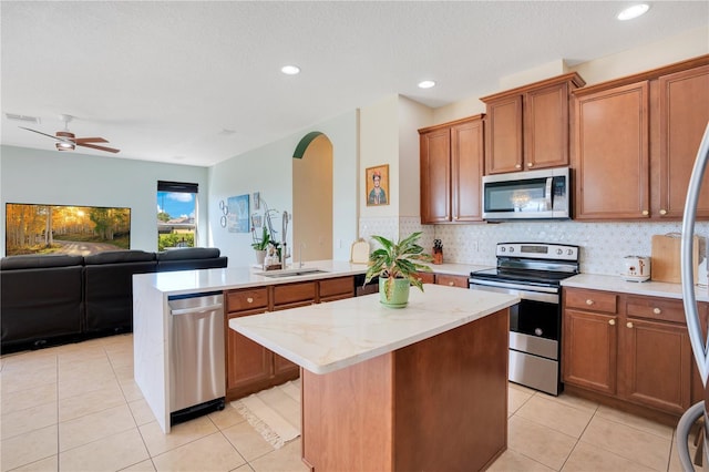 kitchen with a peninsula, stainless steel appliances, open floor plan, backsplash, and a center island