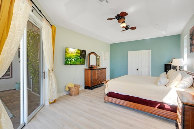 bedroom with visible vents, access to outside, wood finished floors, baseboards, and a raised ceiling