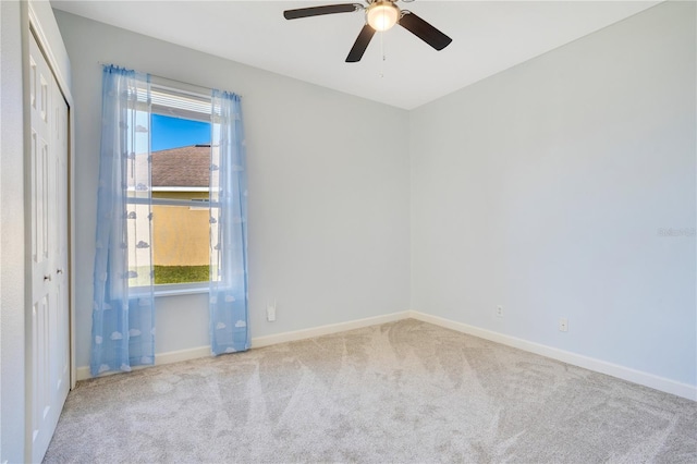 empty room featuring a healthy amount of sunlight, baseboards, carpet, and ceiling fan